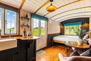A cozy cabin interior with a kitchen, a dining area, and a bed. - Golden Grape in Oakengrove Vineyard (Buckinghamshire)