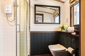Un baño con ducha, inodoro, espejo y lavamanos.