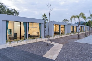 A modern hotel with large windows, a gravel courtyard, and a wooden deck.