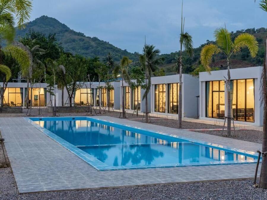 Un complexe hôtelier moderne doté d’une piscine, de palmiers et offrant une vue sur les montagnes.