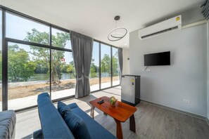 A modern room with a large window, a flat-screen TV, a small table, and a sofa.