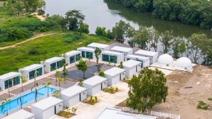 Un hotel moderno con piscina, estructuras en forma de cúpula blanca y vistas al río.