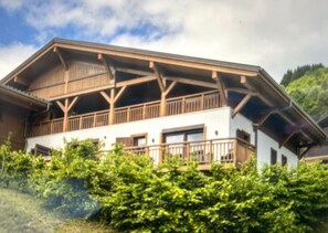 A two-story building with a balcony, surrounded by greenery. - Apartment Le Rouge Gorge (Les Gets)