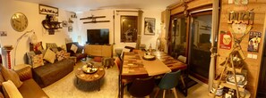 A cozy living room with a TV, sofa, coffee table, and a dining area with a wooden table and chairs. - Apartment Le Rouge Gorge (Les Gets)