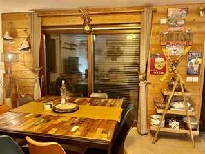 A dining area with a wooden table, chairs, a bottle, and glasses. - Apartment Le Rouge Gorge (Les Gets)