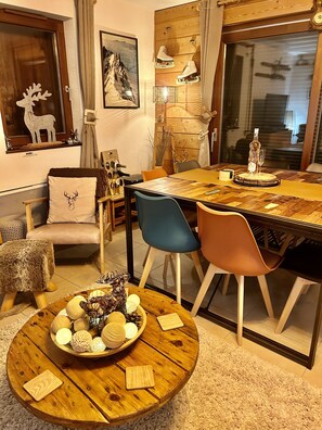 A cozy dining area with a wooden table, chairs, and a round wooden table with decorative items. - Apartment Le Rouge Gorge (Les Gets)