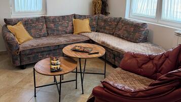 Un salon avec un canapé d’angle, une table basse ronde et un fauteuil rouge.