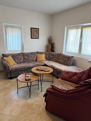 A living room with a sectional sofa, a round coffee table, and a red armchair.