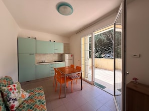 Eine kompakte Küche mit Esstisch und Stühlen, einer Couch und einer Glastür zu einem Balkon.