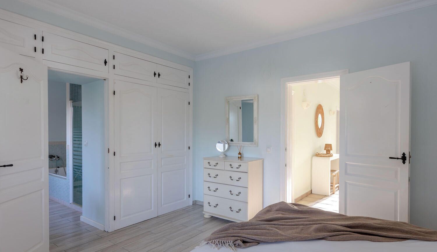 Un dormitorio con cama, cómoda, espejo y armario.