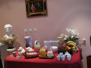 Ein Frühstücksbuffet mit einer Statue, Kaffeeautomaten, Obst und Milchprodukten.