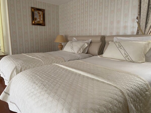 Ein Doppelbett mit gesteppter Bettdecke, eine Nachttischlampe und ein gerahmtes Bild an der Wand.