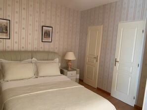 A bedroom with a bed, a nightstand, a lamp, and two doors.