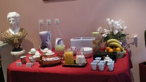 Un bufé de desayuno con una estatua, cafeteras, fruta y productos lácteos.