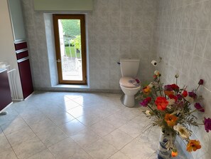 A bathroom with a toilet, a window, and a vase of flowers. - Le Relais Des Hirondelles - Magnolia Room with Private Garden (Chaumont-en-Vexin)