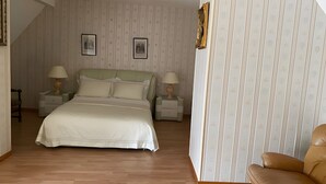 Un dormitorio con una cama, dos mesitas de noche con lámparas, una silla y una escalera.