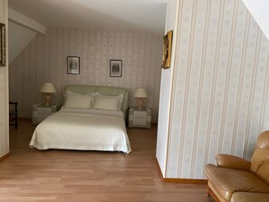 A bedroom with a bed, two bedside tables with lamps, a chair, and a staircase. - Le Relais Des Hirondelles - Magnolia Room with Private Garden (Chaumont-en-Vexin)