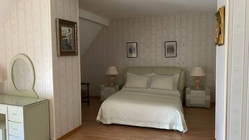 Une chambre à coucher comprenant un lit, deux tables de chevet, une commode, une coiffeuse, un miroir et un tableau encadré accroché au mur.