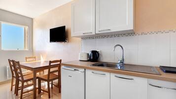 Een moderne keuken met witte kasten, een houten eettafel en stoelen.