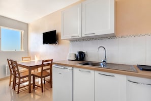 A modern kitchen with white cabinets, a wooden dining table, and chairs.
