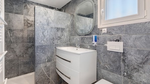 Une salle de bain moderne avec un meuble-lavabo blanc, un miroir et un espace douche.