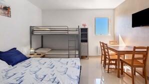 Une petite pièce comprenant un lit superposé, un bureau et une chaise.