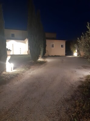 Uma entrada pavimentada que leva a um edifício com telhado de telhas e uma pequena janela.