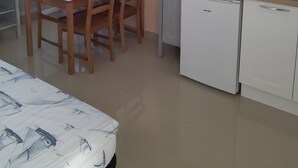 Cocina compacta con mesa, sillas, televisor, cafetera y lavavajillas.