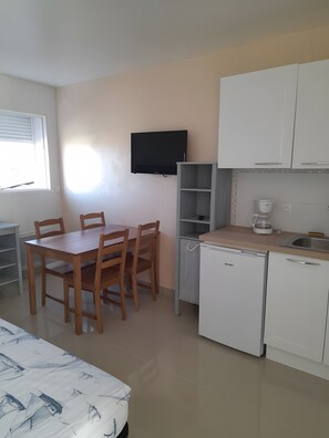 A compact kitchen with a dining table, chairs, a TV, a coffee maker, and a dishwasher. - Ceraria Apartment with Shared Pool (Loupian)