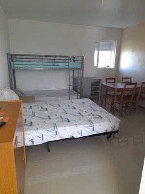 Um quarto com beliches, uma escrivaninha e uma mesa de jantar com cadeiras.