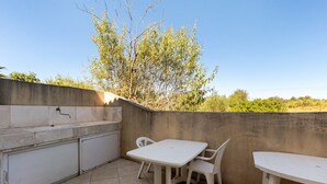 Une terrasse extérieure équipée d’un évier, de deux chaises et d’une table.