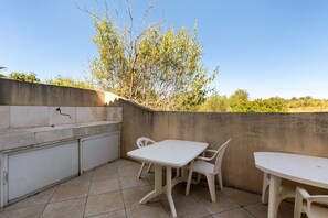 An outdoor patio with a sink, two chairs, and a table.