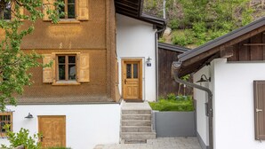 Una casa de dos pisos con puerta de madera, felpudo y una escalera que conduce a la entrada.