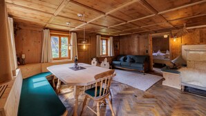 Interior de una cabaña de madera con una mesa de comedor, un sofá, un banco y una cama.