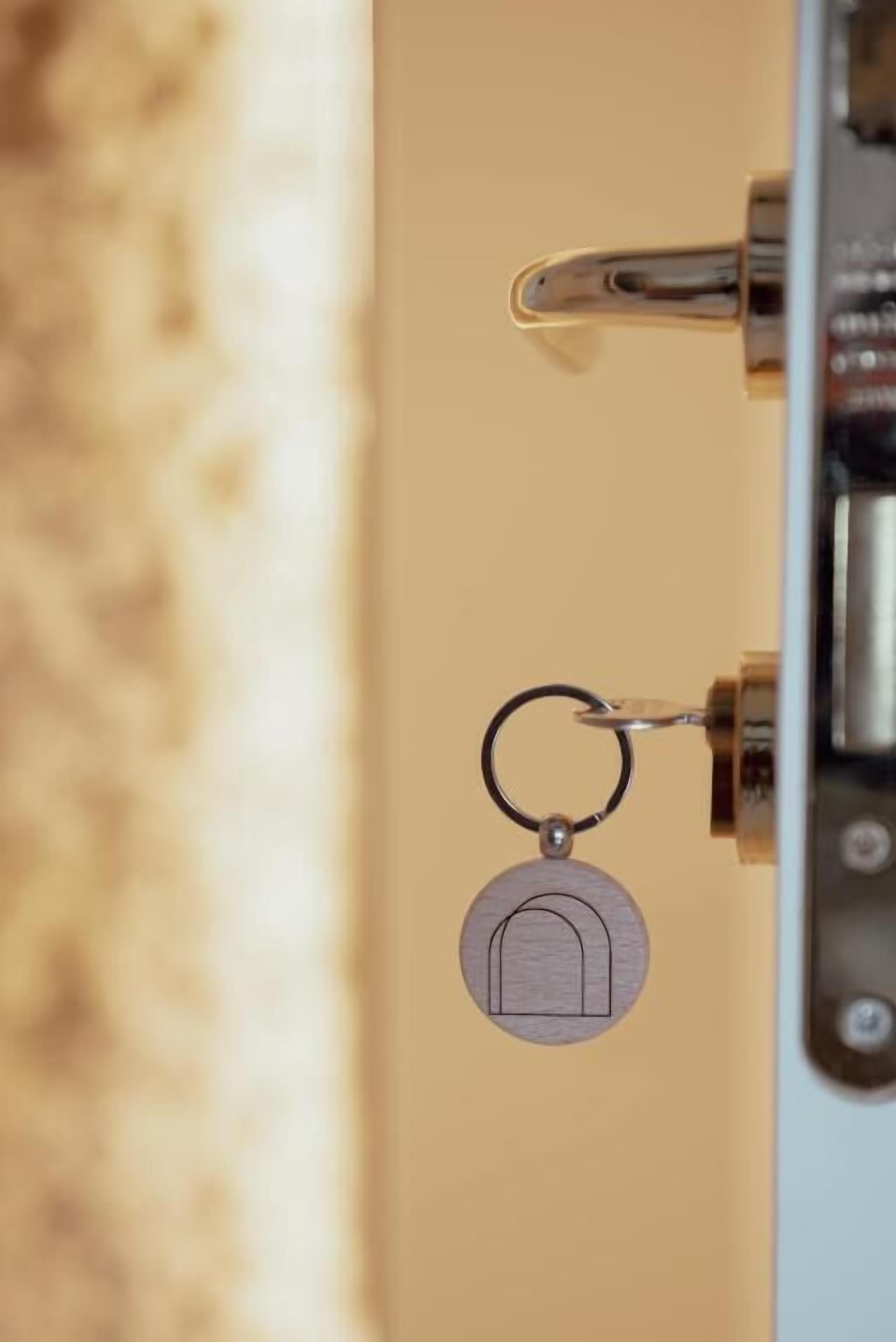 A keychain with a house-shaped keyring attached to a door handle.