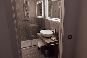 Een moderne badkamer met een ruime wastafel, een douchecabine met glazen wanden en een spiegel boven de wastafel.
