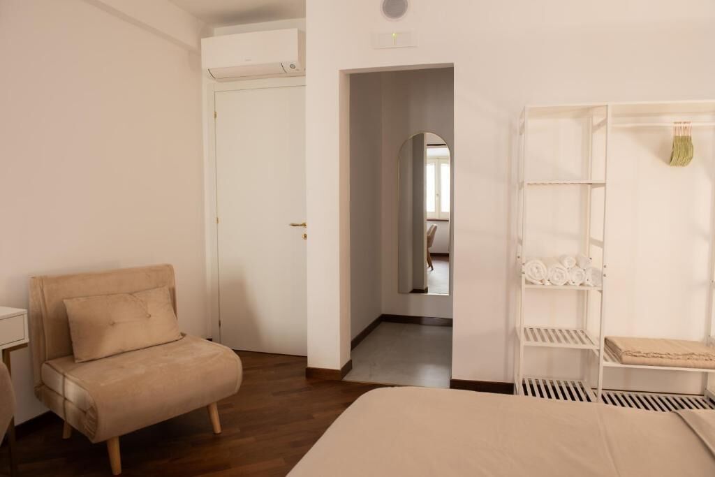 A bedroom with a bed, a sofa, a wardrobe, and a door leading to another room.