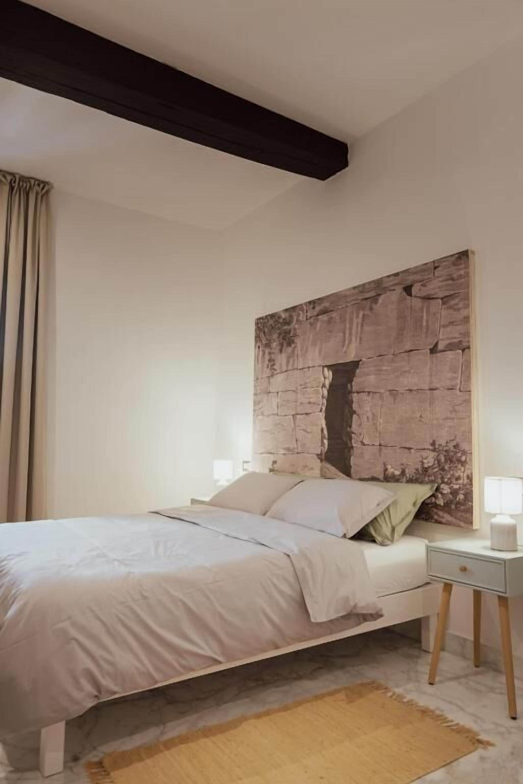 Un dormitorio con cama, mesita de noche y un gran cabecero de madera.