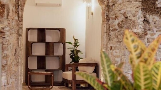 A stone archway leading to a room with a wooden bookshelf, a small table, and a chair. - Ferentino B&B (Ferentino)
