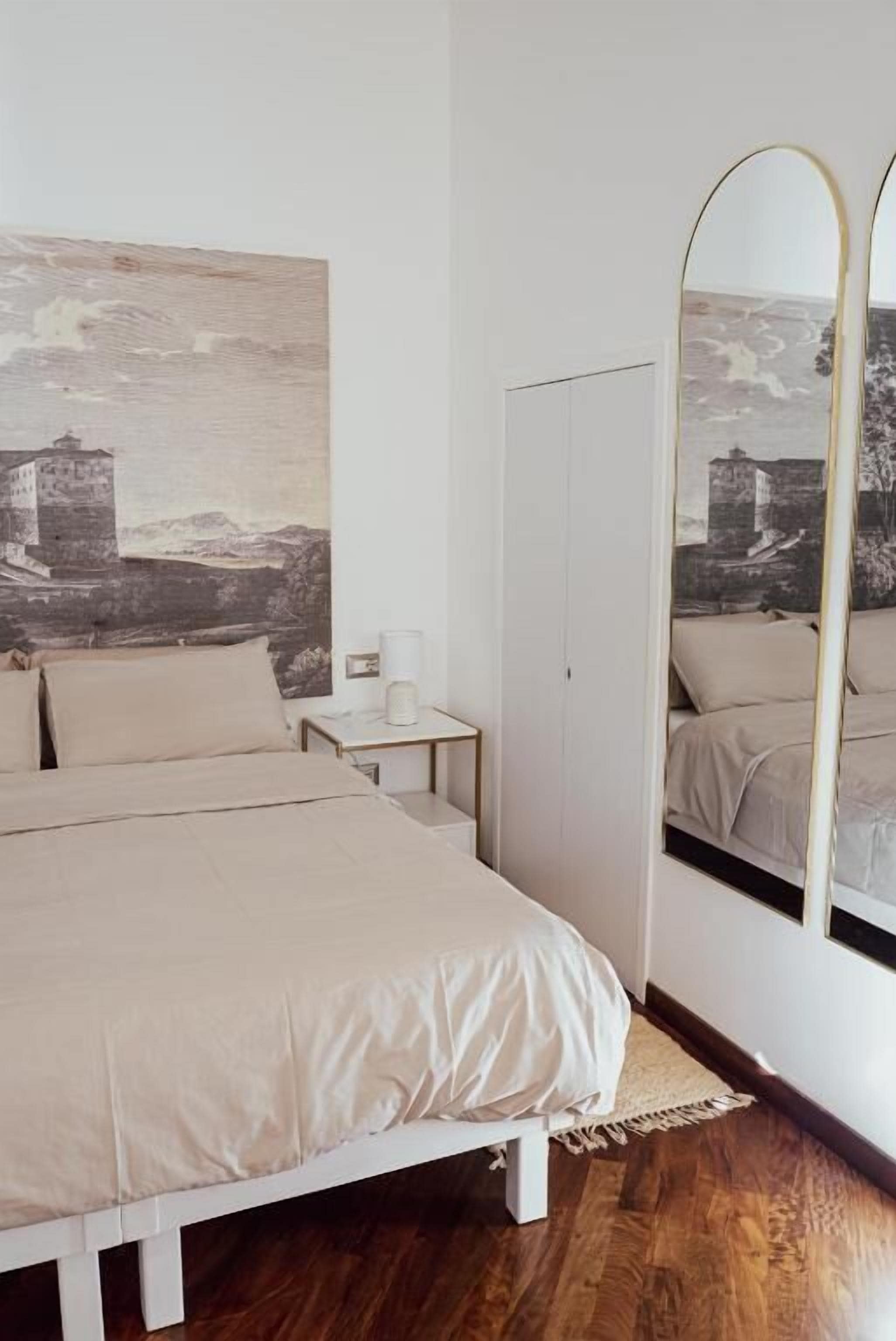 Una camera da letto con un letto, un comodino, uno specchio e un grande quadro a parete.
