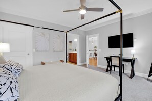 A bedroom with a large bed, a desk, a chair, a television, and a ceiling fan. - Sleeps 18, 3 Suites | Walkable Historic District | The Juliette by AvantStay (Savannah)