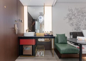 Una moderna camera d'hotel con un grande specchio, un lavandino, un divano verde e una parete con un disegno a tema urbano.