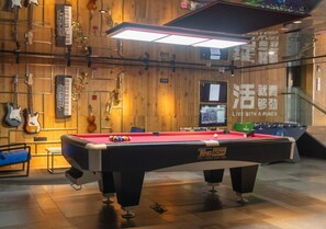 Un tavolo da biliardo in una stanza con pareti in legno, strumenti musicali e un tavolo da calcio.