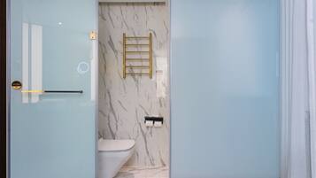 A modern bathroom with a glass partition, a marble wall, a toilet, and a towel rack.