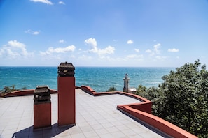 Une terrasse avec vue sur la mer, un phare et une construction en pierre.