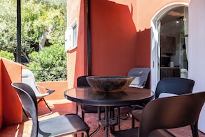 A patio with a round table, chairs, and a stone bowl. - Casa Orizzonte-Vista Sul Mare Del Circeo (Punta Rossa)