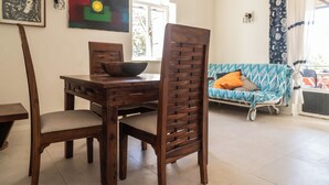 A dining area with a wooden table and chairs, a sofa with patterned cushions, and artwork on the walls. - Casa Orizzonte-Vista Sul Mare Del Circeo (Punta Rossa)