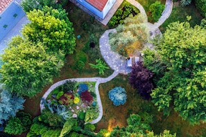 Vista aérea de um jardim ajardinado com caminhos, arbustos de formas variadas e uma pequena área de estar.