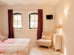 Une chambre avec deux lits, une chaise, un téléviseur et une lampe.