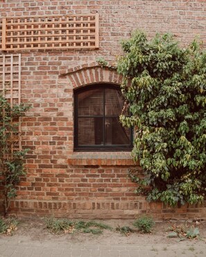 Ein Backsteinhaus mit einem Fenster, einem Holzgitter und einer mit Efeu bewachsenen Mauer.